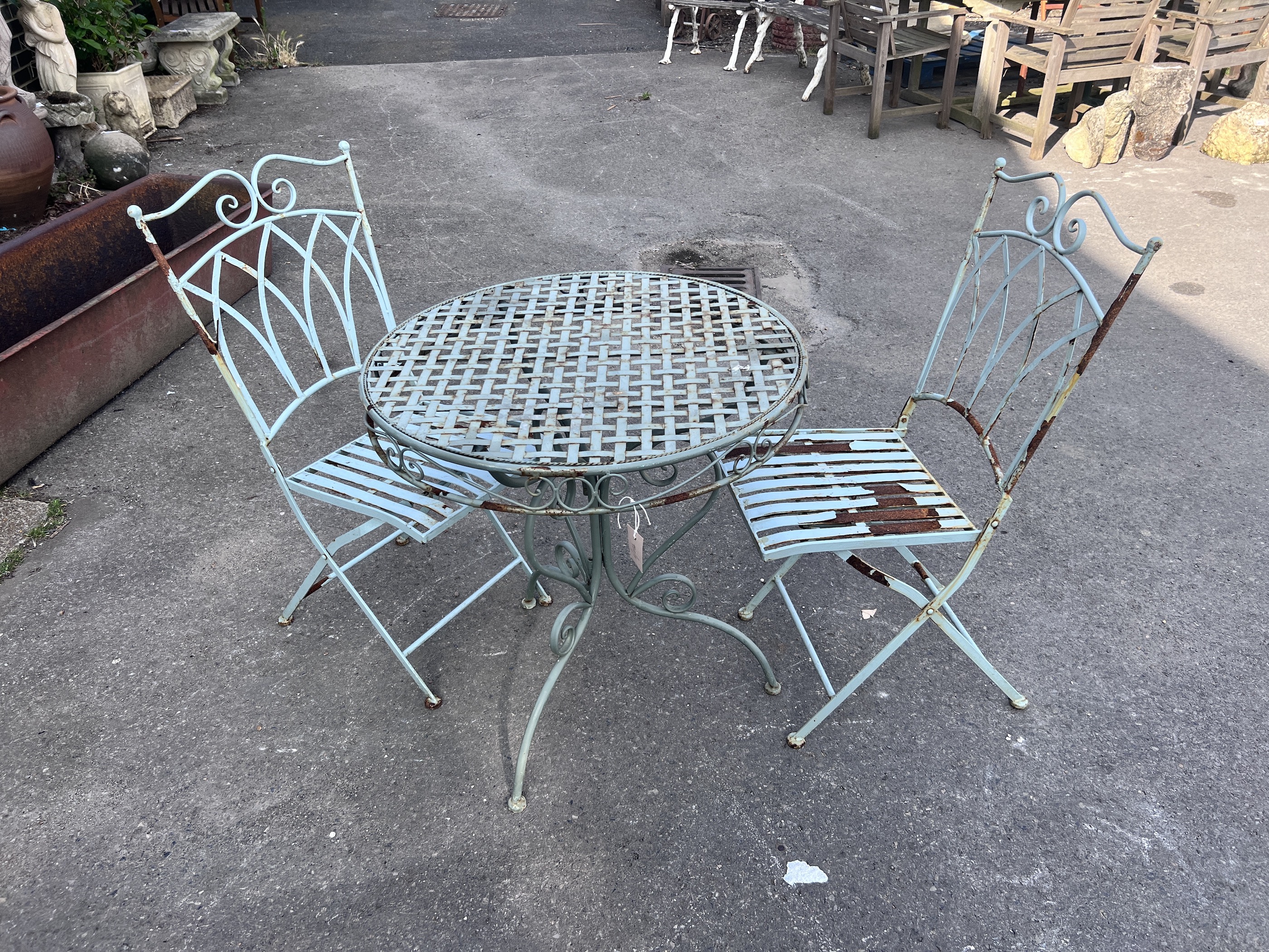 A circular painted metal garden table, diameter 70cm, height 74cm, and two chairs